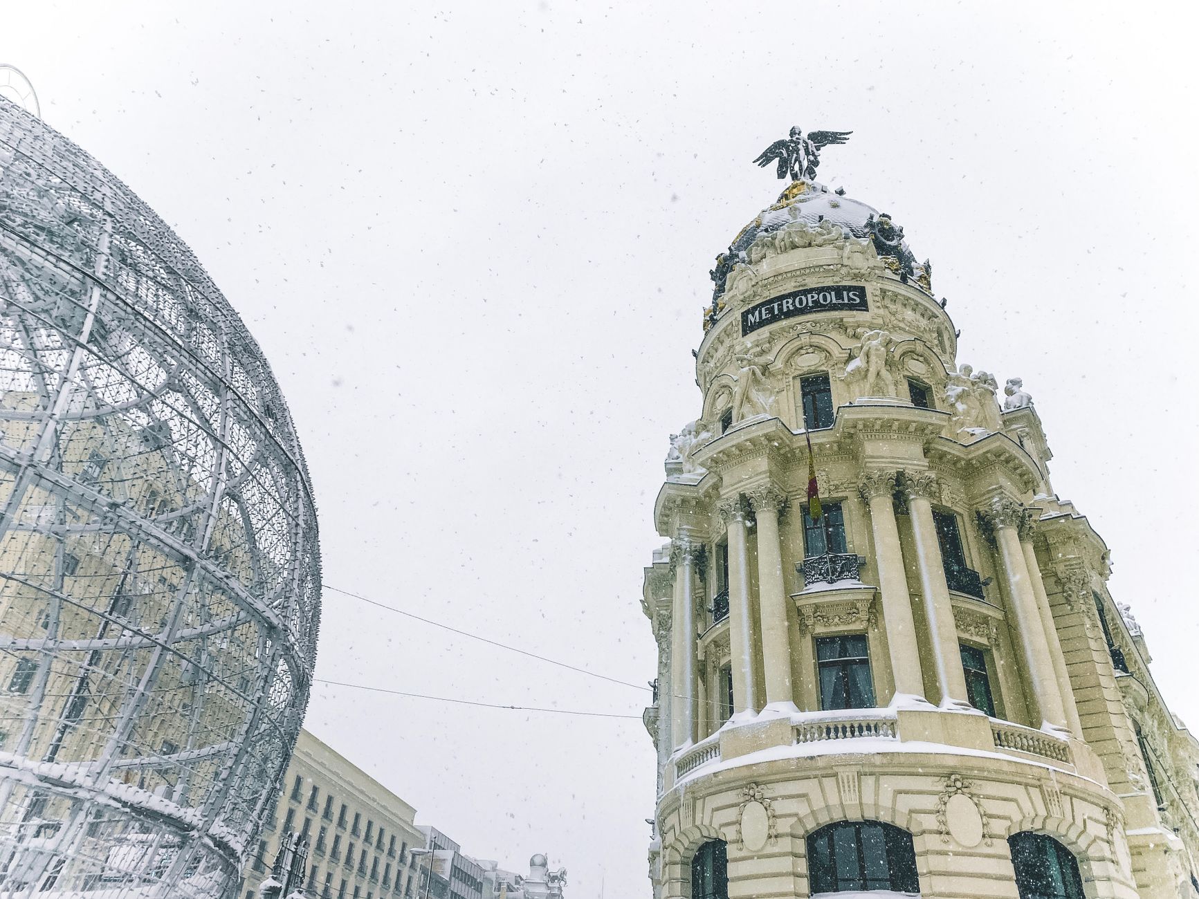Low-angle shot of the Metropolis Building in Madrid during a snowy winter day.