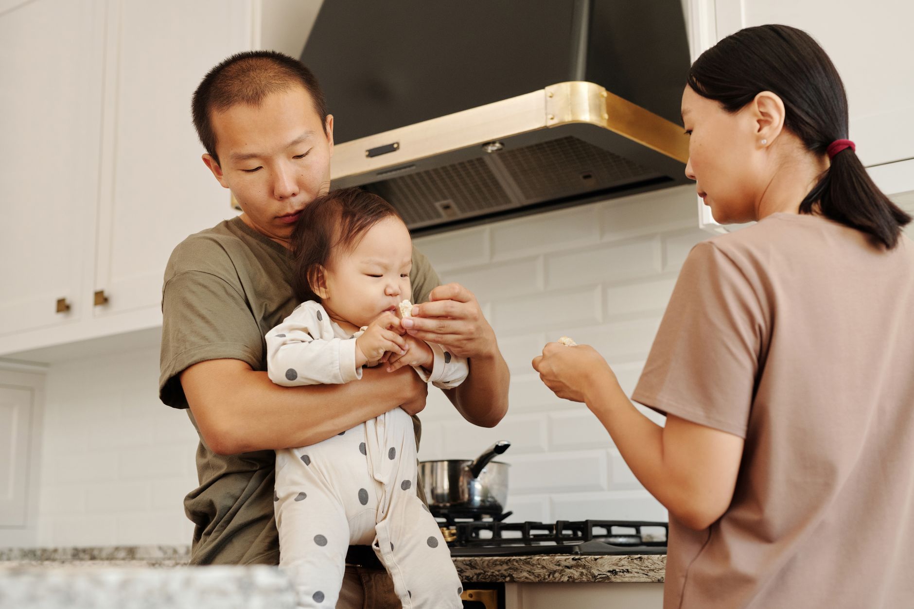 Family feeding time in a cozy kitchen as parents care for their baby.