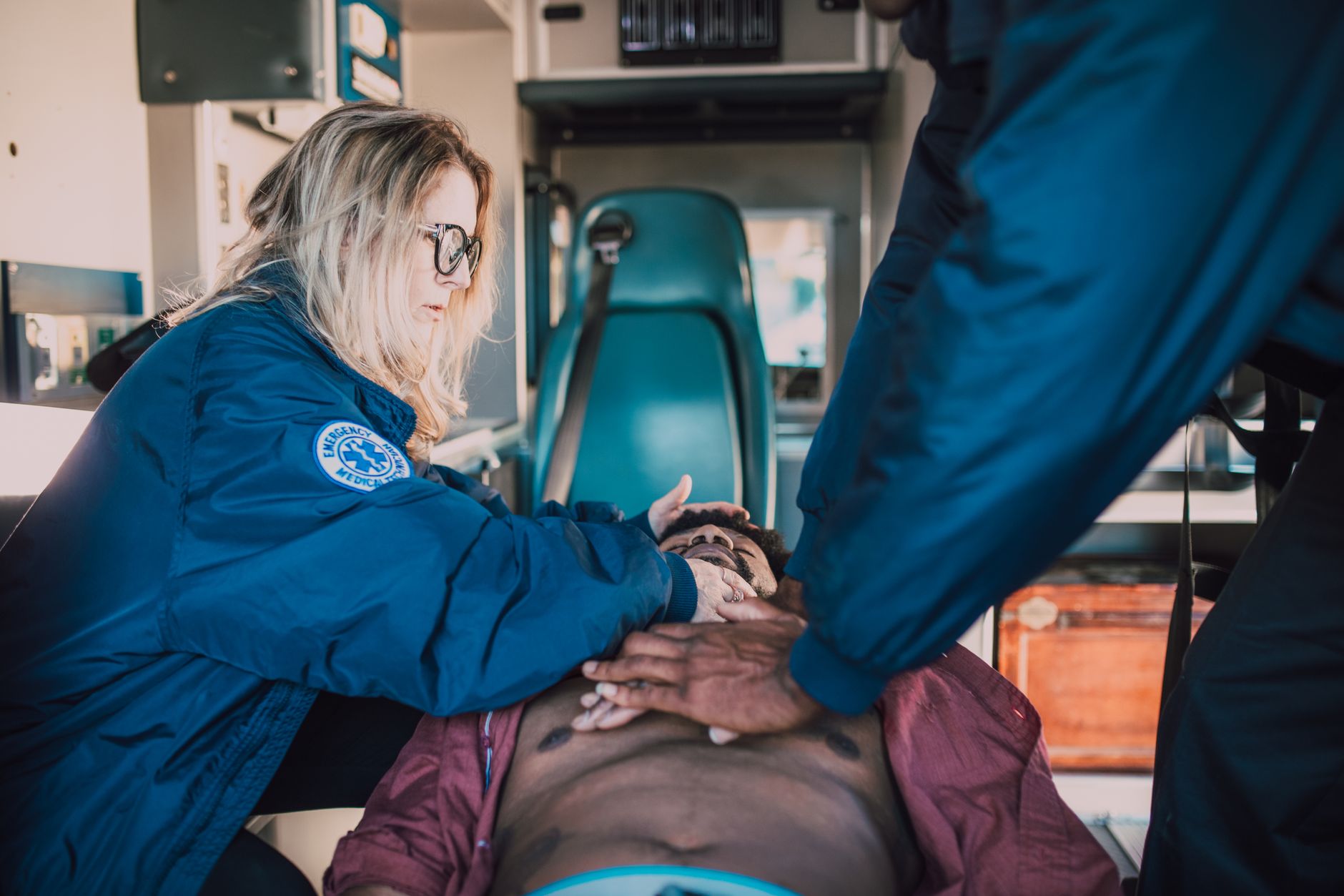 Emergency responders performing CPR on patient in ambulance setting.
