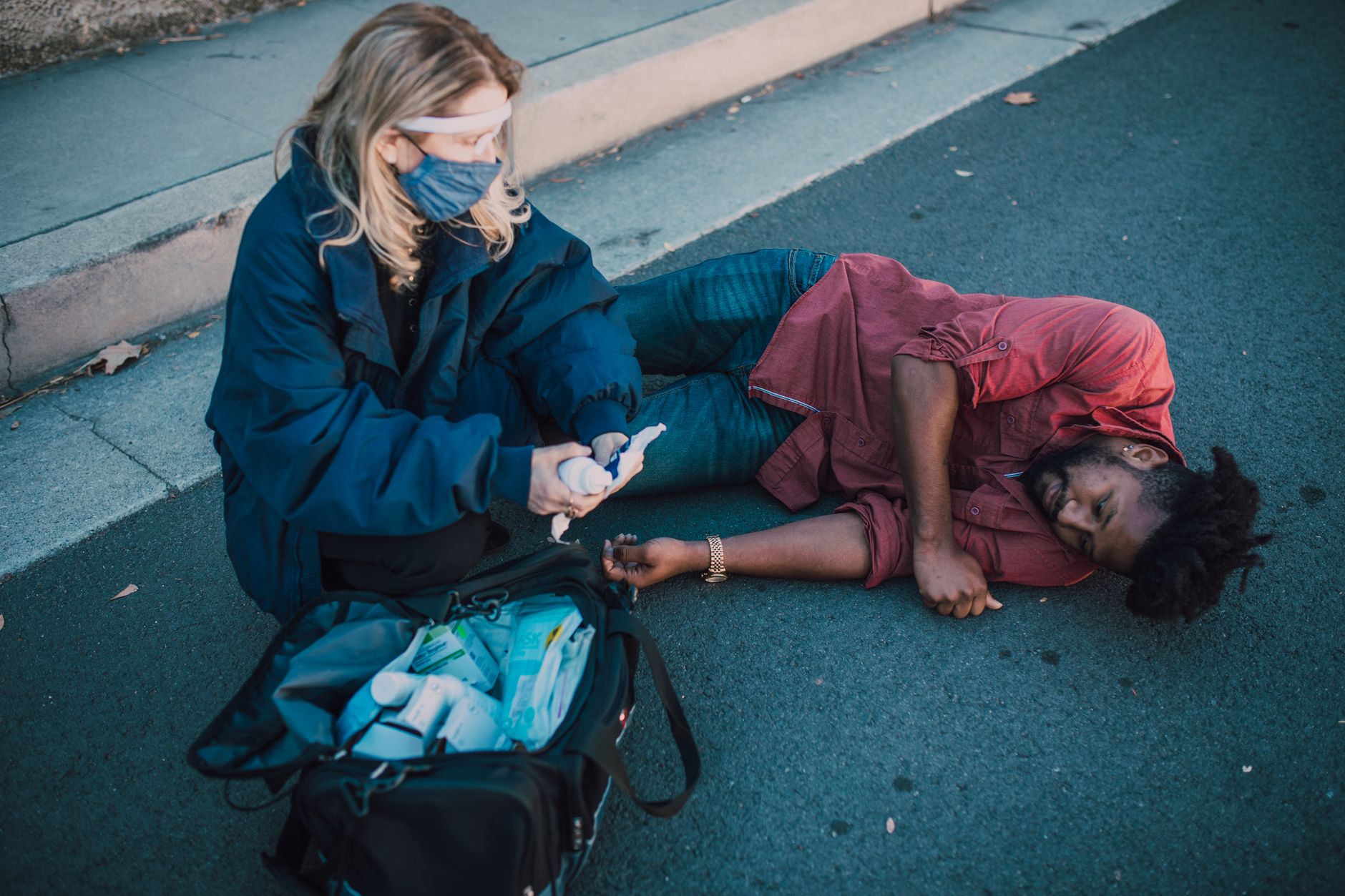 Paramedic provides first aid to injured man lying on roadside.