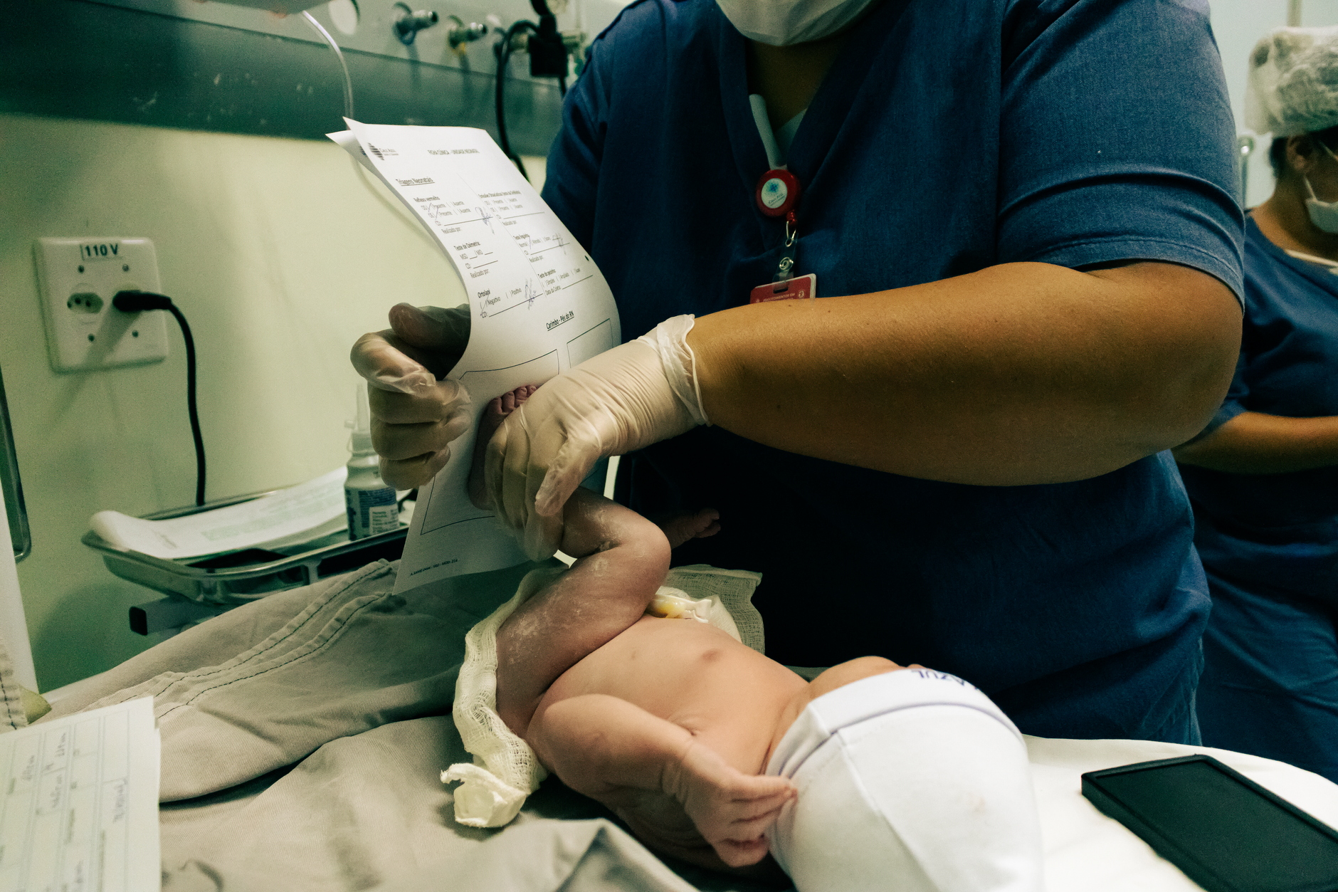Healthcare professional handling a newborn in São Paulo hospital, ensuring crucial initial care.