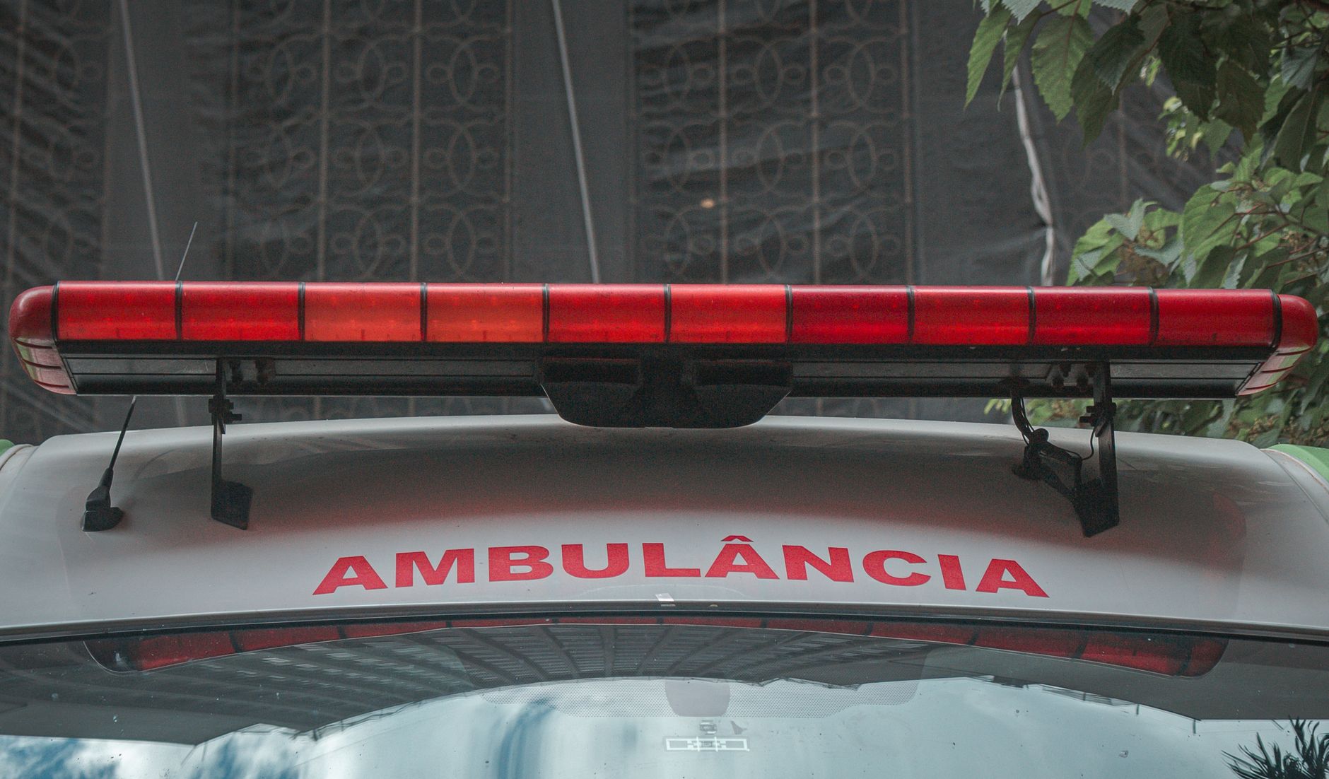 A close-up view of a city ambulance with a red siren light and Portuguese text 'AMBULÂNCIA'
