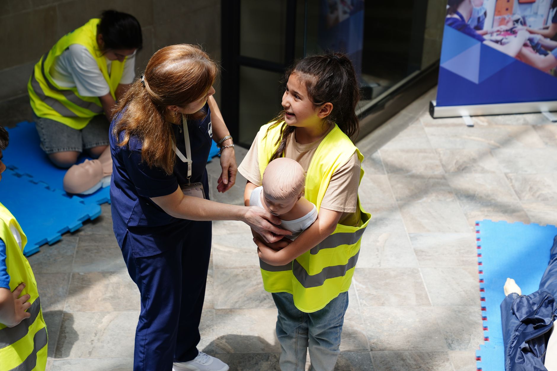 Child participates in a hands-on first aid class learning infant care with an instructor.