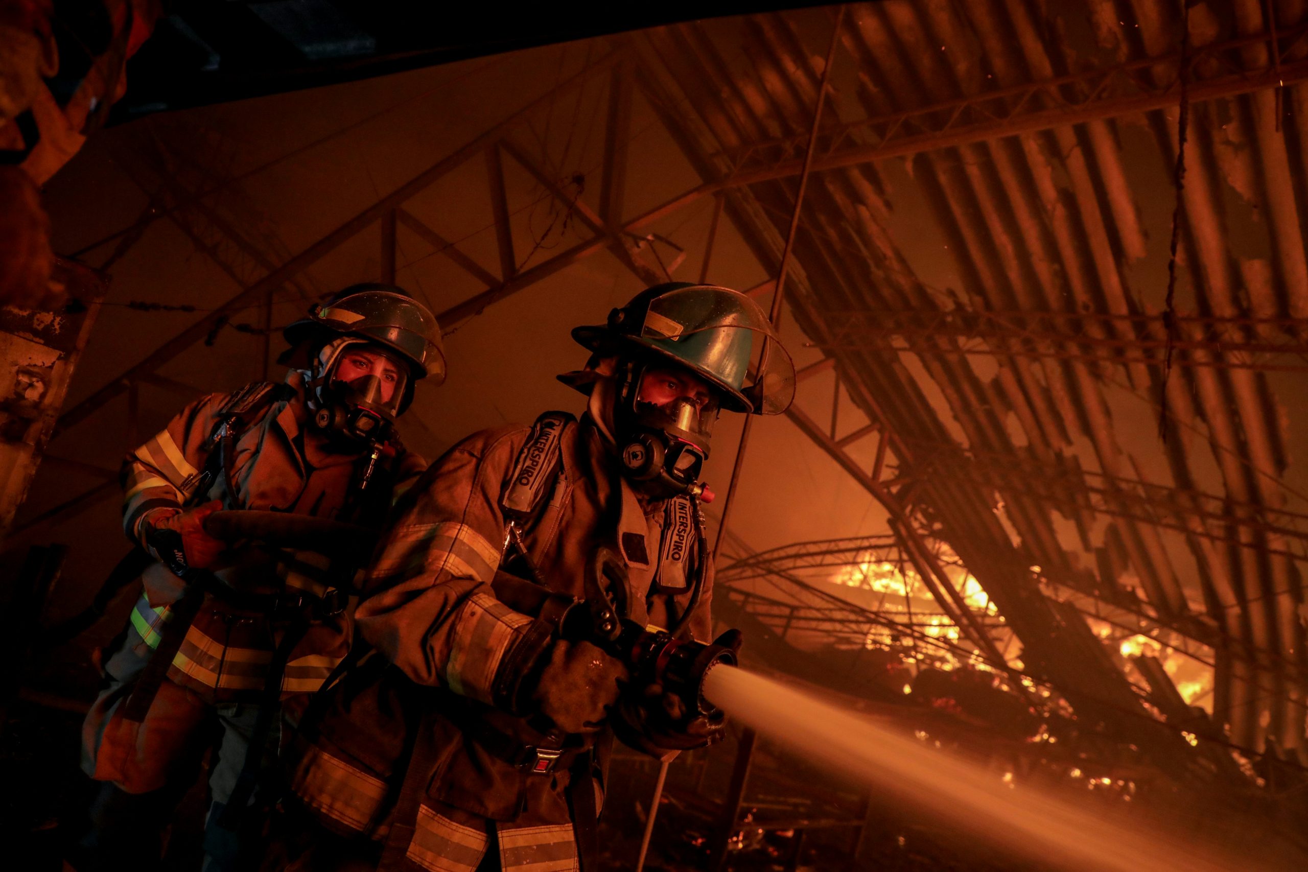 Firefighters combat a blaze with a water hose.